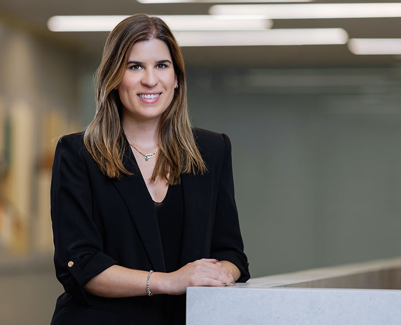 Luciana Figueiredo Rocha  Mulher de cabelo castanho na altura dos ombros. Veste uma blusa preta e um blazer preto de meia manga. Ela está em pé, com as mãos apoiadas em uma bancada a direita, olhando para frente e sorrindo.