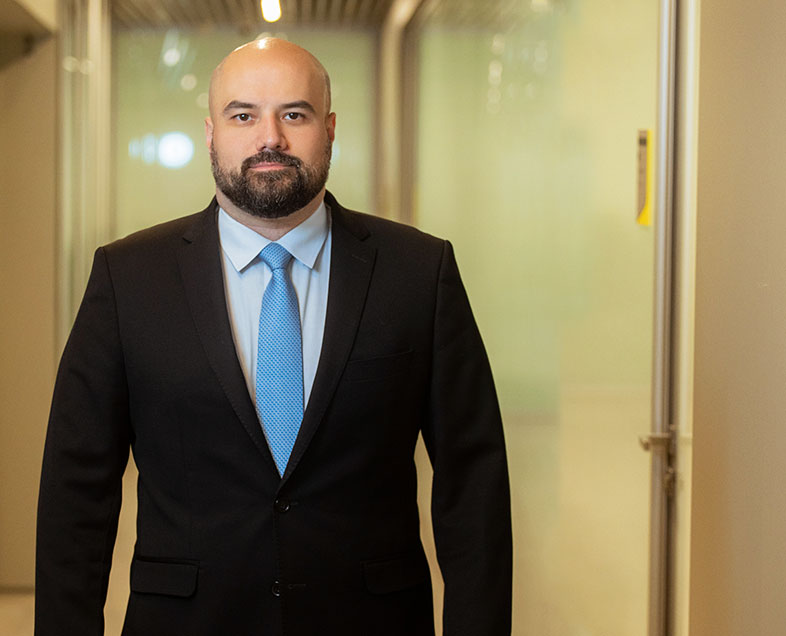 Luiz Antonio Franco  Homem calvo, com bigode e barba pretos medianos. Veste uma camisa branca, terno preto e gravata azul clara. Ele está em pé, olhando para frente.