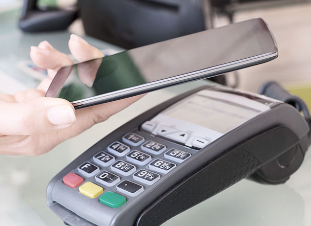 Photo of card machine and cell phone approaching to make payment