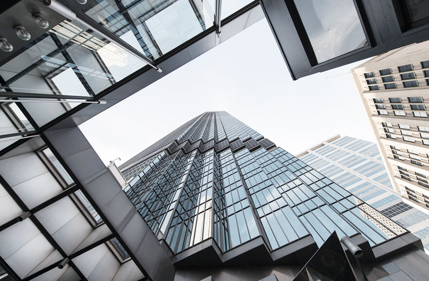 Lower view of a building with a metallic structure and glass panels with a bluish undertone