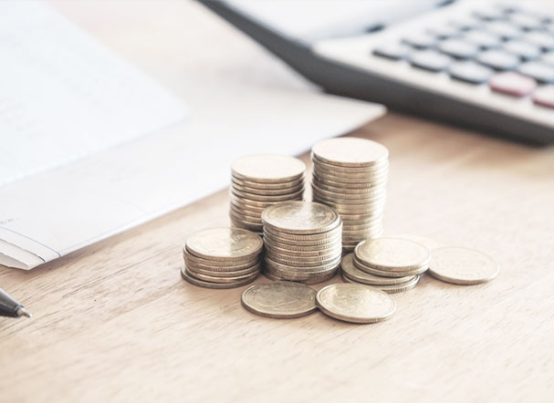 Gold-colored stacks of coins in different sizes. Gray calculator in the background