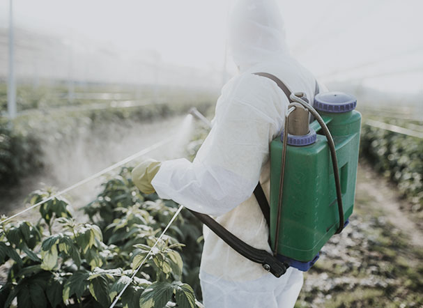 imagem de homem uniformizado com equipamento de pulverização em uma área de cultivação